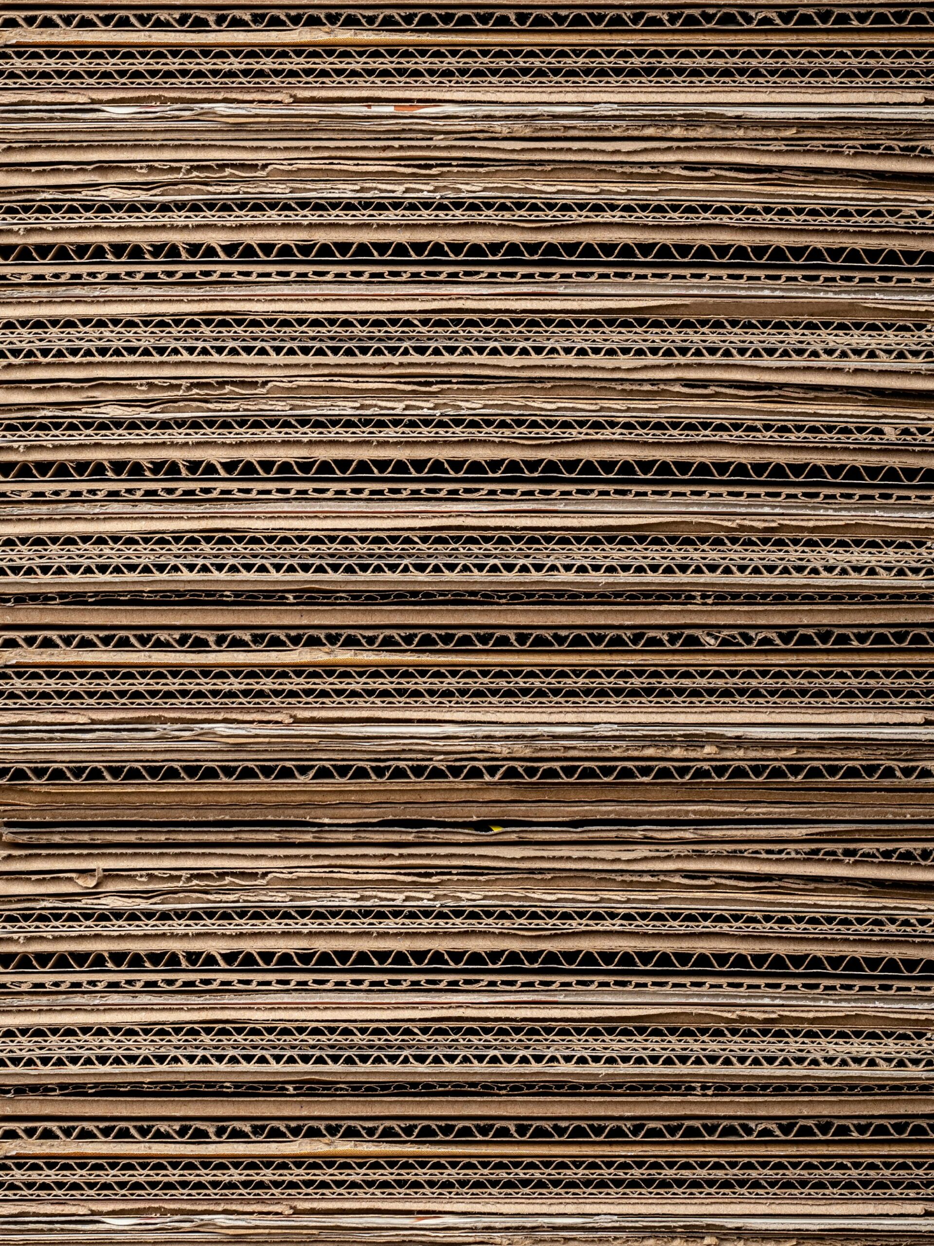 Close-up texture of stacked cardboard for recycling or crafting. Ideal for background use.